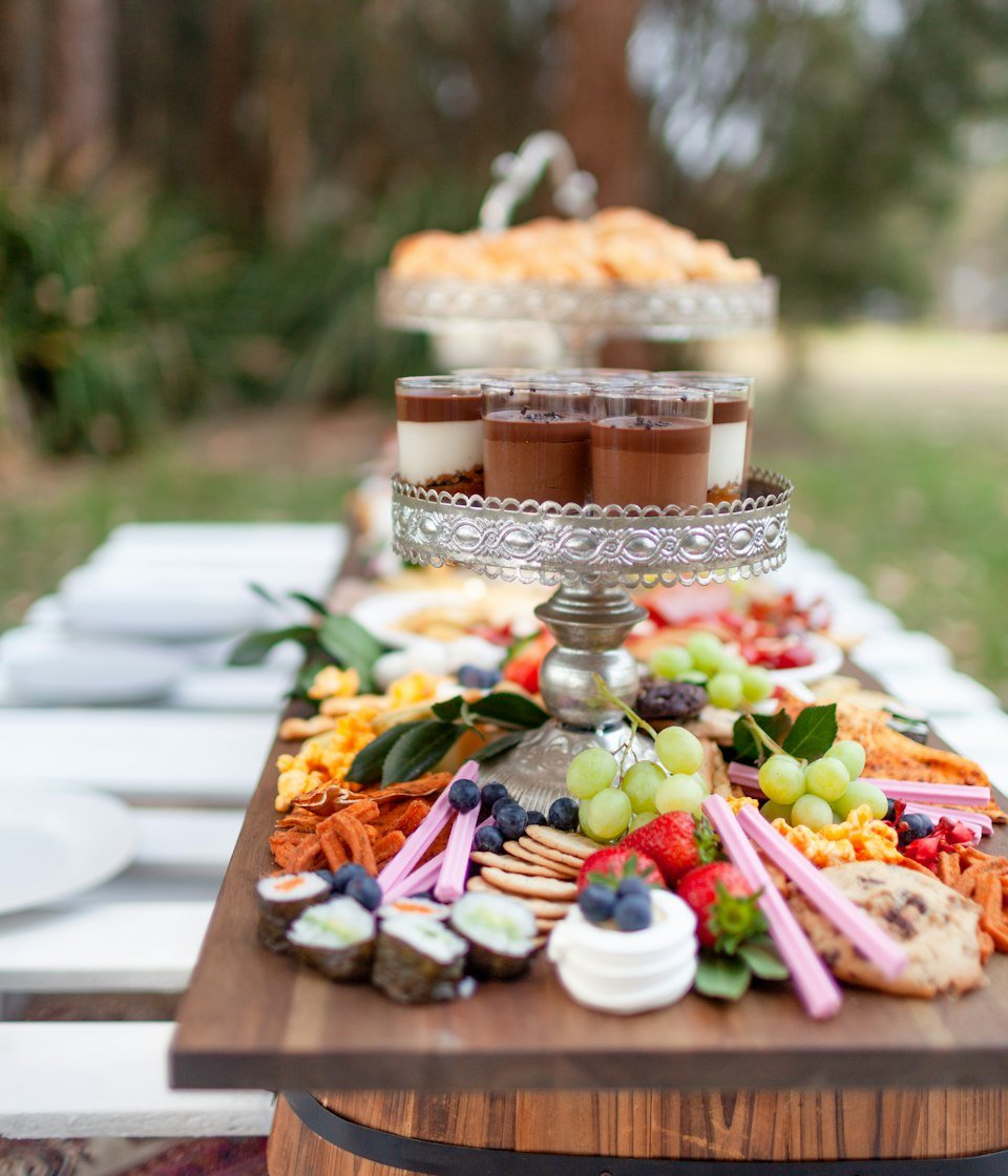 Outdoor grazing table with fruit, charcuterie and a tiered dessert stand